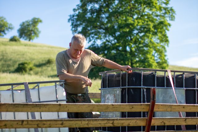 Der Schäfer befestigt Wassertanks für die Weide auf dem Anhänger